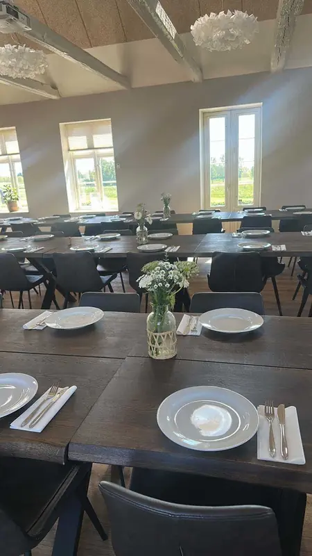 Lys sal med træborde, hvide tallerkener og små buketter med margueritter