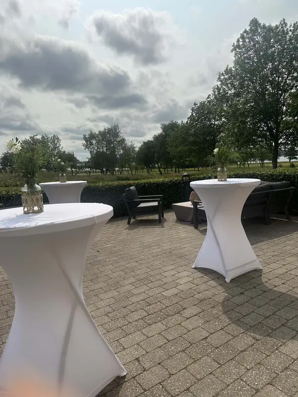 Terrassen med høje ståborde i hvide overtræk og udsigt over golfbanen