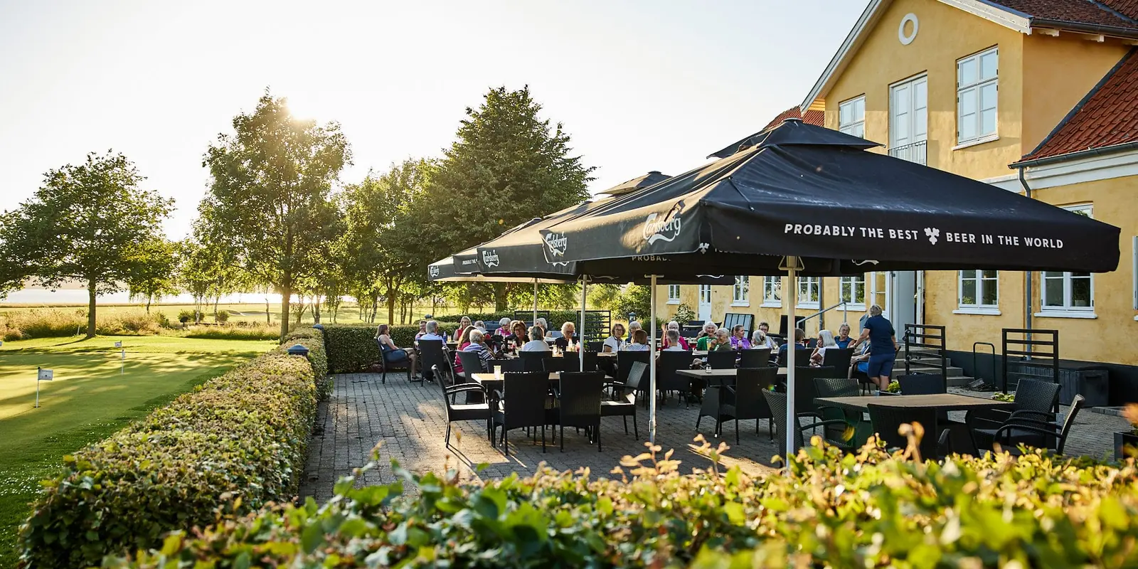 Terrassen ved klubhuset med parasoller og udsigt til golfbanen